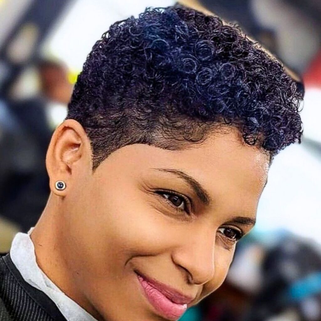 Smiling person with short curly hair and earring